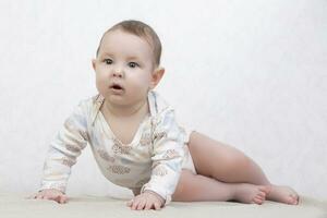 Kid with a smile on a white background. A healthy six-month-old boy lies on the bed. Conceptual photo of fatherhood and motherhood.