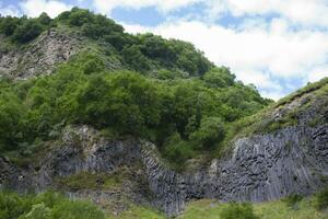 Mountains of mixed geological rocks covered with greenery. photo