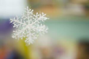 Blurred green and pink background with white artificial snowflake photo