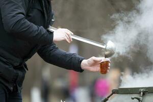 Tea master pours tea in a plastic glass outdoors. photo