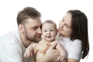 Close up portrait of young parents and baby. Father and mother kiss and hug a beautiful little son. The concept of love, happy fatherhood and motherhood. photo