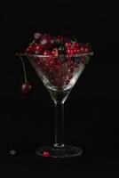Summer berries in a glass glass on a dark background. photo