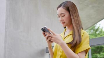 Aziatisch vrouw op zoek Bij haar smartphone jong meisje bezienswaardigheden bekijken video