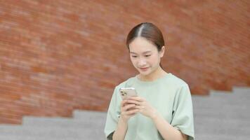 mujer sentado en parque mirando a teléfono inteligente mensajes leer en móvil video