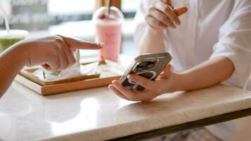 asiatico giovane donne seduta nel bar potabile caffè con amici e parlando insieme video