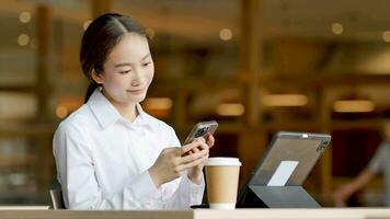 Asian woman sitting and texting on mobile phone video