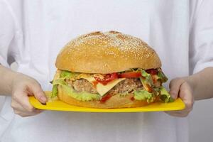 manos sostener un bandeja con un grande hamburguesa. foto