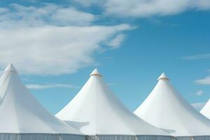 Row of white tent tops under a blue sky photo