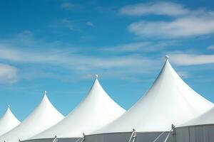 Row of white tent tops under a blue sky photo