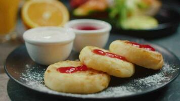 Tasty breakfast. Delicious cheesecakes with jam on a plate, close up video