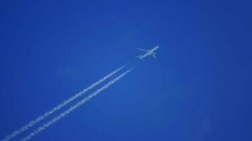 o avião voa alto no céu uma trilha branca. um traço branco de condensação atrás de um avião voando. o rastro de condensação do avião está alto no céu. video