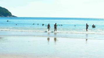silhuetas do veranistas pessoas, turistas dentro a ondas em a nai tocar de praia video