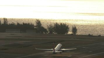 Jet airplane flies over sea at sunset. Vacation, aviation, travel, trip concept, copy space. Modern commercial aircraft take off, climbing over ocean, beautiful sunset on background. video