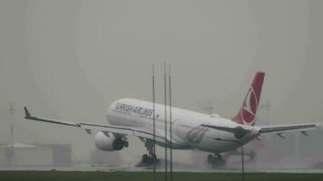 MOSCOW, RUSSIAN FEDERATION JULY 29, 2021 - Airbus A330 of Turkish Airlines landing and touching the runway in rainy weather on an early gray morning video