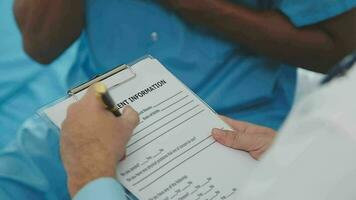 Senior doctor and young male patient who lie on the bed while checking pulse, consult and explain with nurse taking note and supporting in hospital wards. video