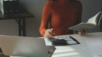 Asian Businesswoman Using laptop computer and working at office with calculator document on desk, doing planning analyzing the financial report, business plan investment, finance analysis concept. video