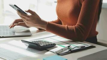 Asian Businesswoman Using laptop computer and working at office with calculator document on desk, doing planning analyzing the financial report, business plan investment, finance analysis concept. video