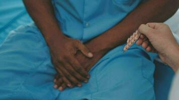 Senior doctor and young male patient who lie on the bed while checking pulse, consult and explain with nurse taking note and supporting in hospital wards. video