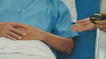 Senior doctor and young male patient who lie on the bed while checking pulse, consult and explain with nurse taking note and supporting in hospital wards. video