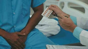 senior dokter en jong mannetje geduldig wie liggen Aan de bed terwijl controle pols, raadplegen en leg uit met verpleegster nemen Notitie en ondersteunen in ziekenhuis afdelingen. video