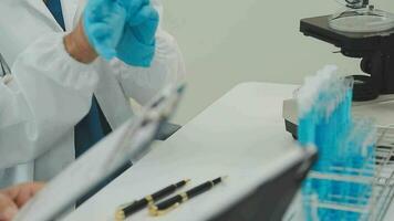 Health care researchers working in life science laboratory. Young female research scientist and senior male supervisor preparing and analyzing microscope slides in research lab. video