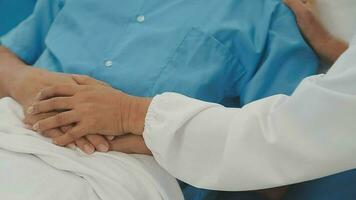 Senior doctor and young male patient who lie on the bed while checking pulse, consult and explain with nurse taking note and supporting in hospital wards. video