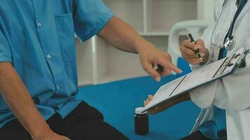 Senior doctor and young male patient who lie on the bed while checking pulse, consult and explain with nurse taking note and supporting in hospital wards. video