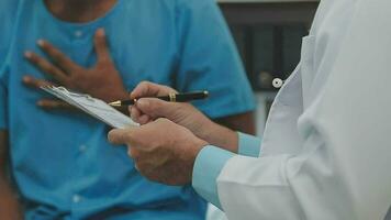 Senior doctor and young male patient who lie on the bed while checking pulse, consult and explain with nurse taking note and supporting in hospital wards. video