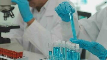 Health care researchers working in life science laboratory. Young female research scientist and senior male supervisor preparing and analyzing microscope slides in research lab. video