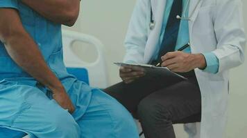 Senior doctor and young male patient who lie on the bed while checking pulse, consult and explain with nurse taking note and supporting in hospital wards. video