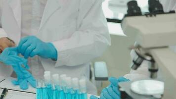 Health care researchers working in life science laboratory. Young female research scientist and senior male supervisor preparing and analyzing microscope slides in research lab. video