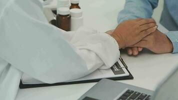 Senior doctor and young male patient who lie on the bed while checking pulse, consult and explain with nurse taking note and supporting in hospital wards. video