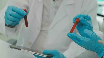 Health care researchers working in life science laboratory. Young female research scientist and senior male supervisor preparing and analyzing microscope slides in research lab. video