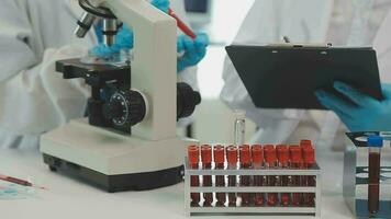 Health care researchers working in life science laboratory. Young female research scientist and senior male supervisor preparing and analyzing microscope slides in research lab. video