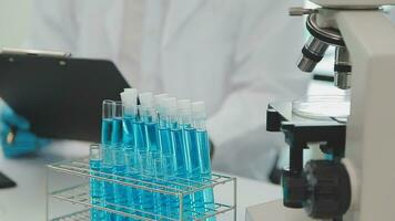 Health care researchers working in life science laboratory. Young female research scientist and senior male supervisor preparing and analyzing microscope slides in research lab. video