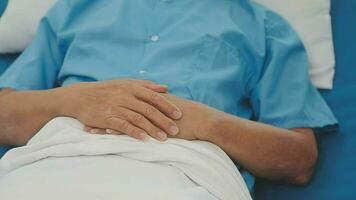 Senior doctor and young male patient who lie on the bed while checking pulse, consult and explain with nurse taking note and supporting in hospital wards. video