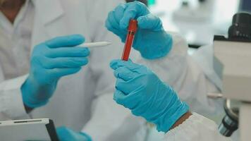 Health care researchers working in life science laboratory. Young female research scientist and senior male supervisor preparing and analyzing microscope slides in research lab. video