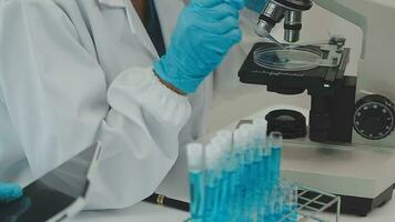 Health care researchers working in life science laboratory. Young female research scientist and senior male supervisor preparing and analyzing microscope slides in research lab. video