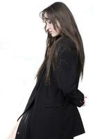 perfil retrato de un hermosa niña con largo pelo en un negro chaqueta en un blanco antecedentes. foto
