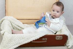 Funny kid sits in an old suitcase. photo