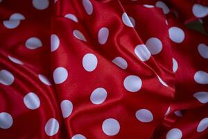 Red silk fabric with large white polka dots. Polka dot background. photo