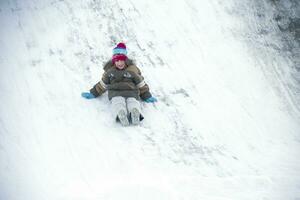 The boy drives off a snow slide photo