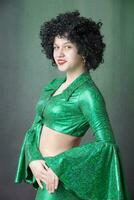 Beautiful vintage woman in an afro wig on a gray background. Disco girl. photo