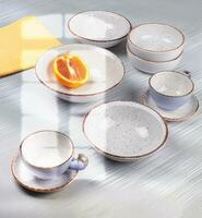 Ceramic bowls and cups are laid out on the table and illuminated by the light from the window. photo