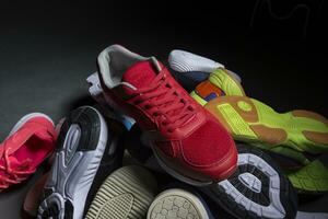 Multi-colored sneakers are stacked in a pile on a gray background. Sport shoes. photo