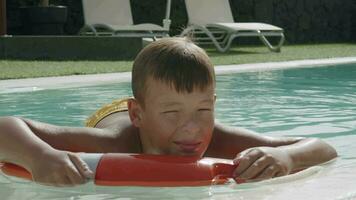 oggi lui è pure pigro per nuotare. rilassato ragazzo galleggiante su sicurezza squillare nel il piscina video