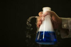 Chemical flask with a blue solution in the hands of a laboratory assistant. Experiences and experiments. photo