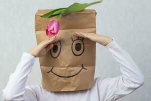 The child has a cardboard box on his head, on which a smile is drawn with a felt-tip pen. The concept of an unexpected gift. photo