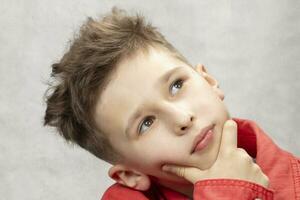 Thoughtful little child in a denim jacket on a white background. photo