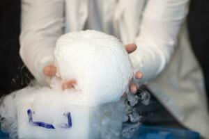 Laboratory chemistry experiment with foam and steaming.Laboratory chemical experiment with foam and steam. Hands holding foam. photo